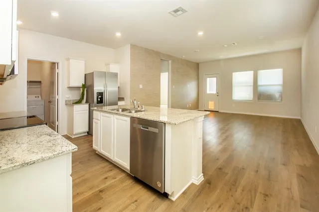 a large kitchen with stainless steel appliances kitchen island a large counter top and a wooden floors