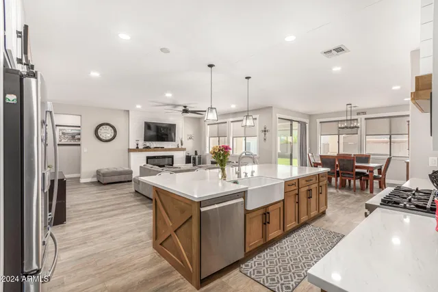 a large kitchen with stainless steel appliances kitchen island granite countertop a large stove a sink dishwasher and white cabinets with wooden floor