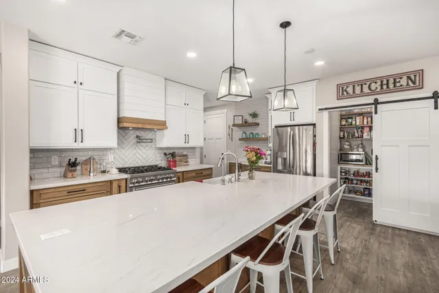 a kitchen with granite countertop a table chairs stainless steel appliances and cabinets