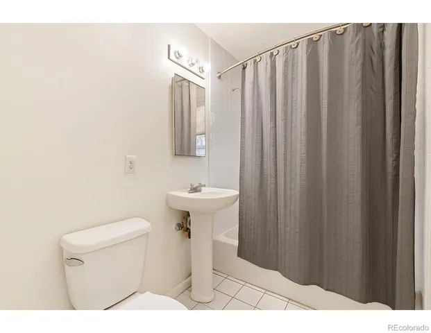 a bathroom with a sink a toilet a mirror and shower curtain