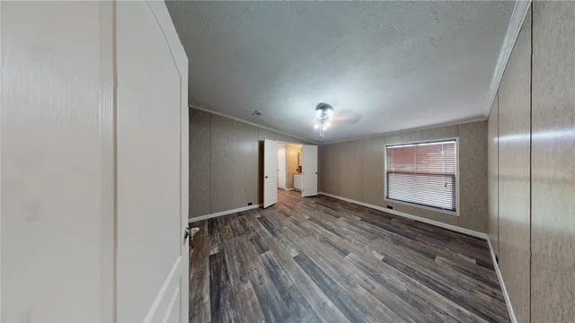an empty room with wooden floor cabinet and windows
