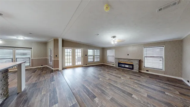 an empty room with fireplace wooden floor and windows