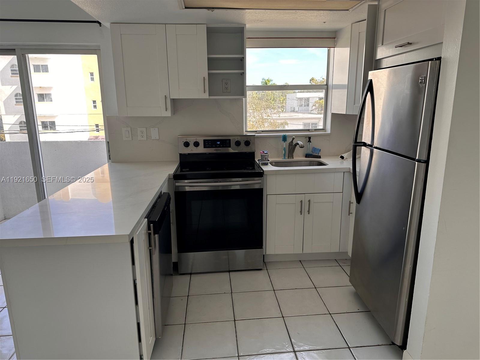 3052 Southwest 27th Avenue, Unit 301 Miami, FL 33133 - Photo 18 of 21 a kitchen with a stove a refrigerator and a sink