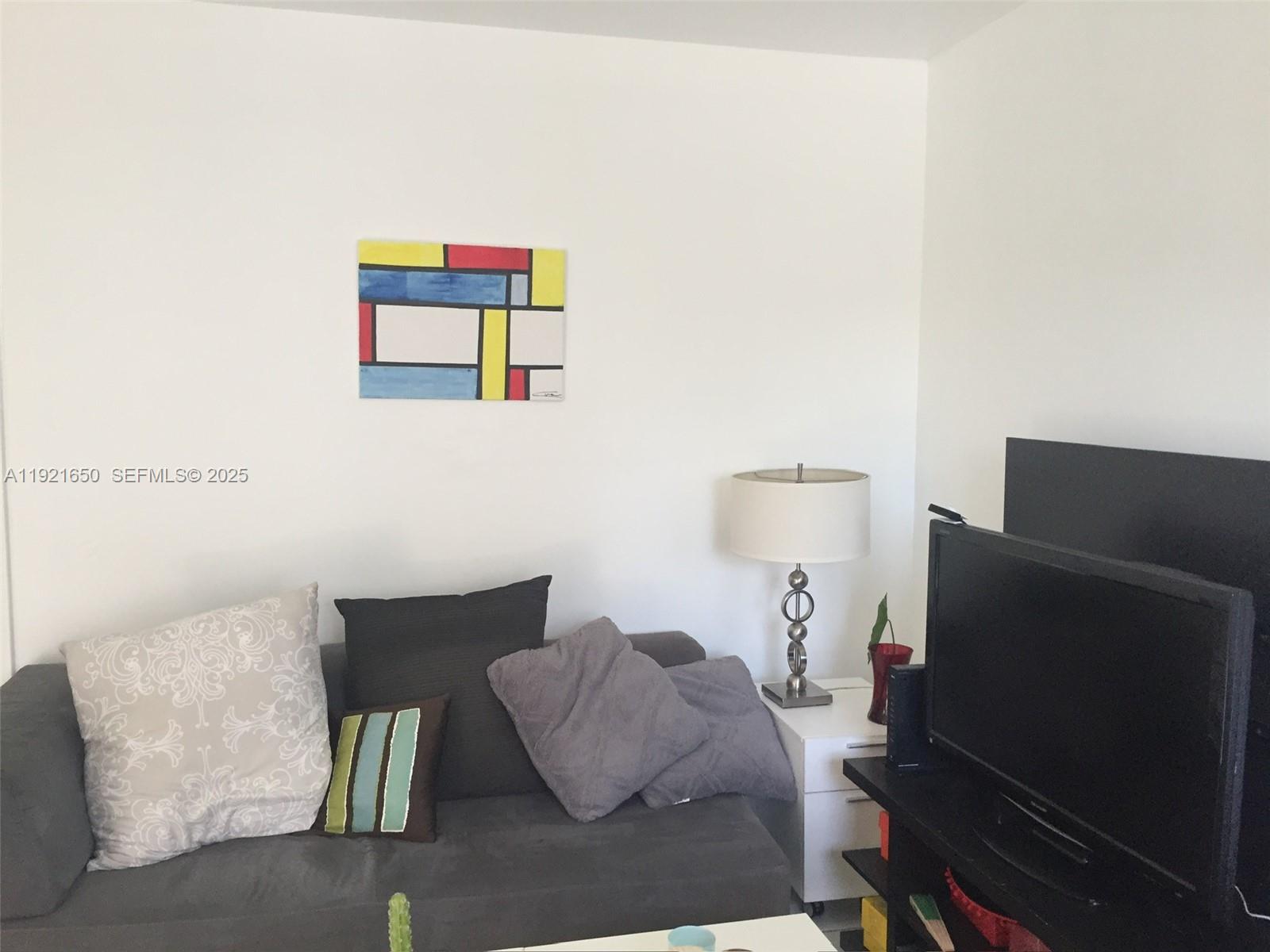 3052 Southwest 27th Avenue, Unit 301 Miami, FL 33133 - Photo 5 of 21 a bedroom with furniture and a lamp