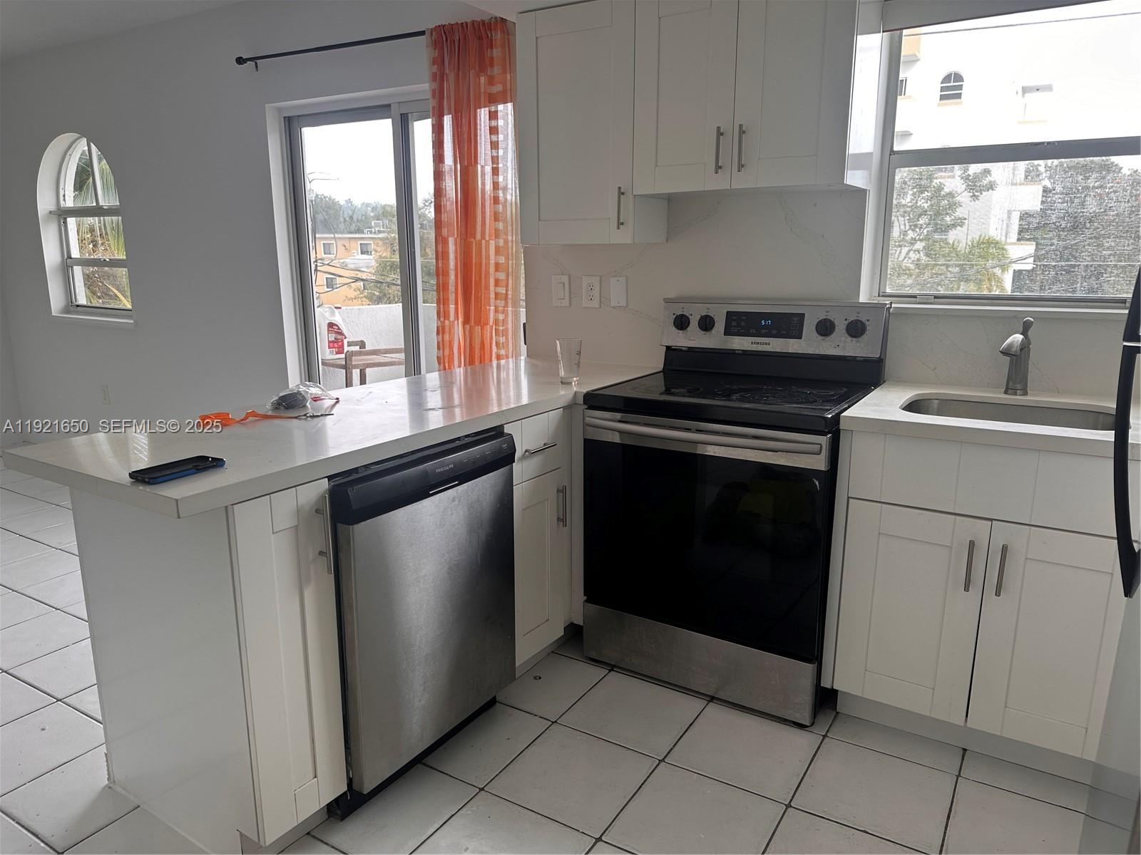3052 Southwest 27th Avenue, Unit 301 Miami, FL 33133 - Photo 7 of 21 a kitchen with a stove a sink and a window