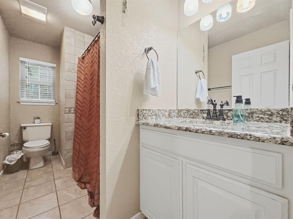 206 Navajo Trail Hamilton, TX 76531 - Photo 20 of 39 Full bath featuring a shower stall, a textured wall, vanity, and light tile patterned floors