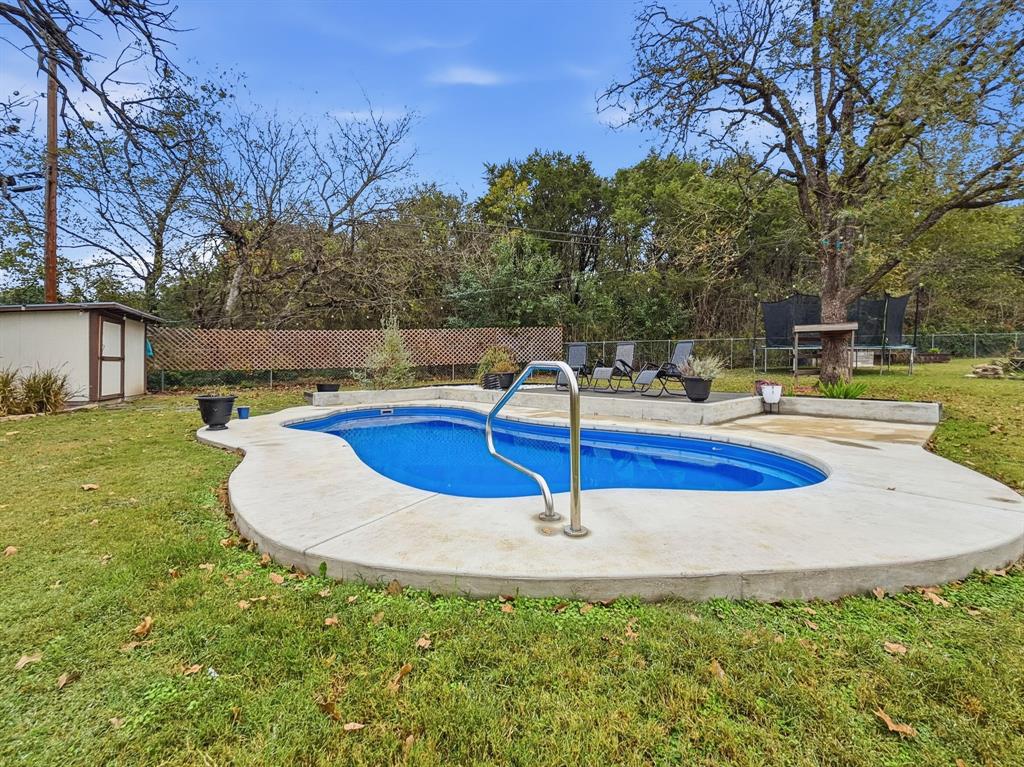 206 Navajo Trail Hamilton, TX 76531 - Photo 31 of 39 View of swimming pool featuring a fenced backyard, a shed, a patio, and view of scattered trees
