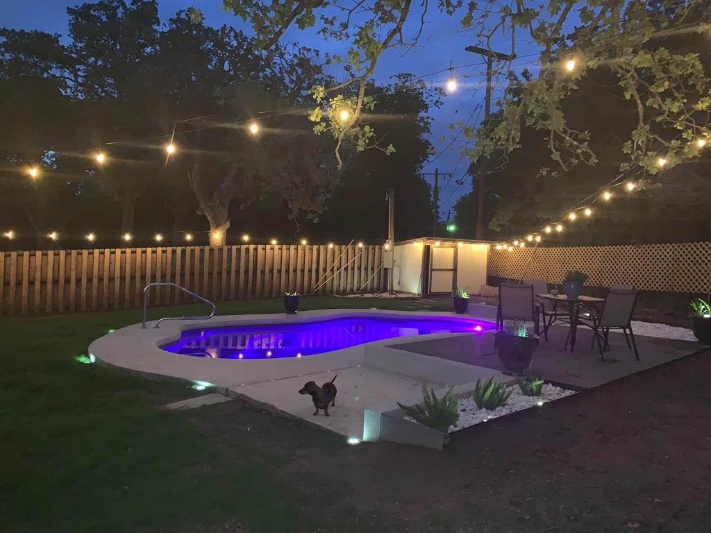 206 Navajo Trail Hamilton, TX 76531 - Photo 33 of 39 Pool at night with a patio, a fenced backyard, and an outbuilding