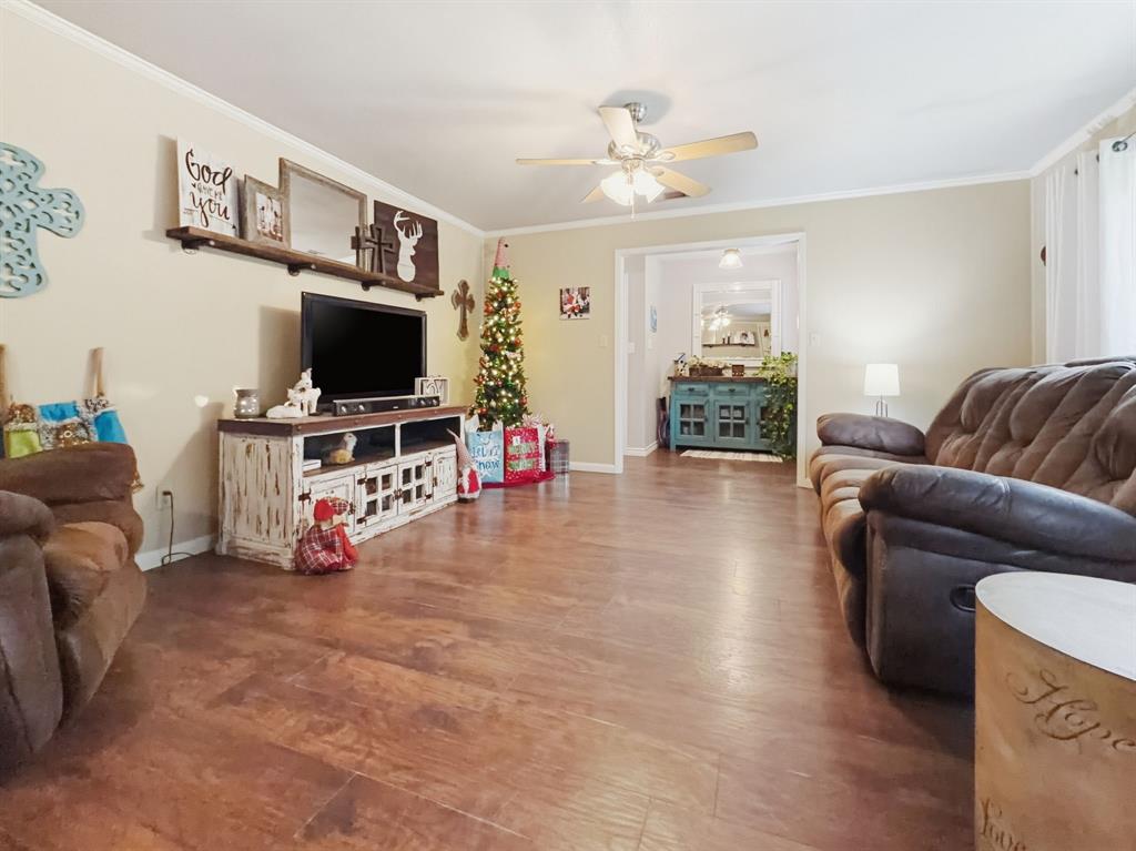 206 Navajo Trail Hamilton, TX 76531 - Photo 7 of 39 Living area with ornamental molding, wood finished floors, and a ceiling fan