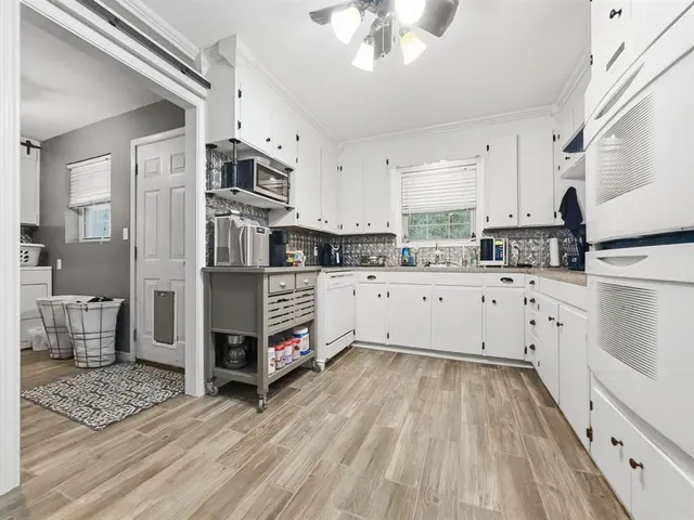 a kitchen with stainless steel appliances a stove top oven a sink a refrigerator white cabinets and wooden floor