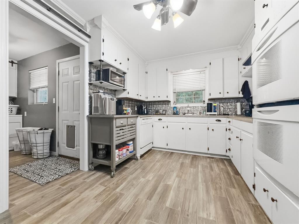 206 Navajo Trail Hamilton, TX 76531 - Photo 8 of 39 Kitchen with white cabinetry, light wood finished floors, ceiling fan, white appliances, and light countertops