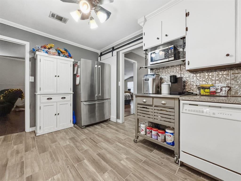 206 Navajo Trail Hamilton, TX 76531 - Photo 10 of 39 Kitchen featuring stainless steel appliances, a barn door, crown molding, wood tiled floors, and white cabinetry