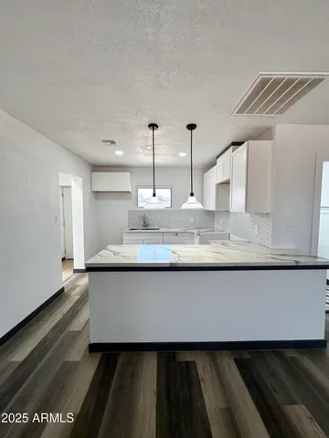 a large kitchen with granite countertop a stove a sink and a granite countertops with wooden floor