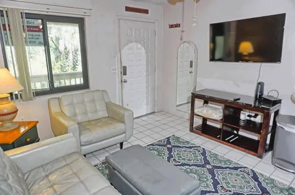 a living room with furniture a flat screen tv and a floor to ceiling window