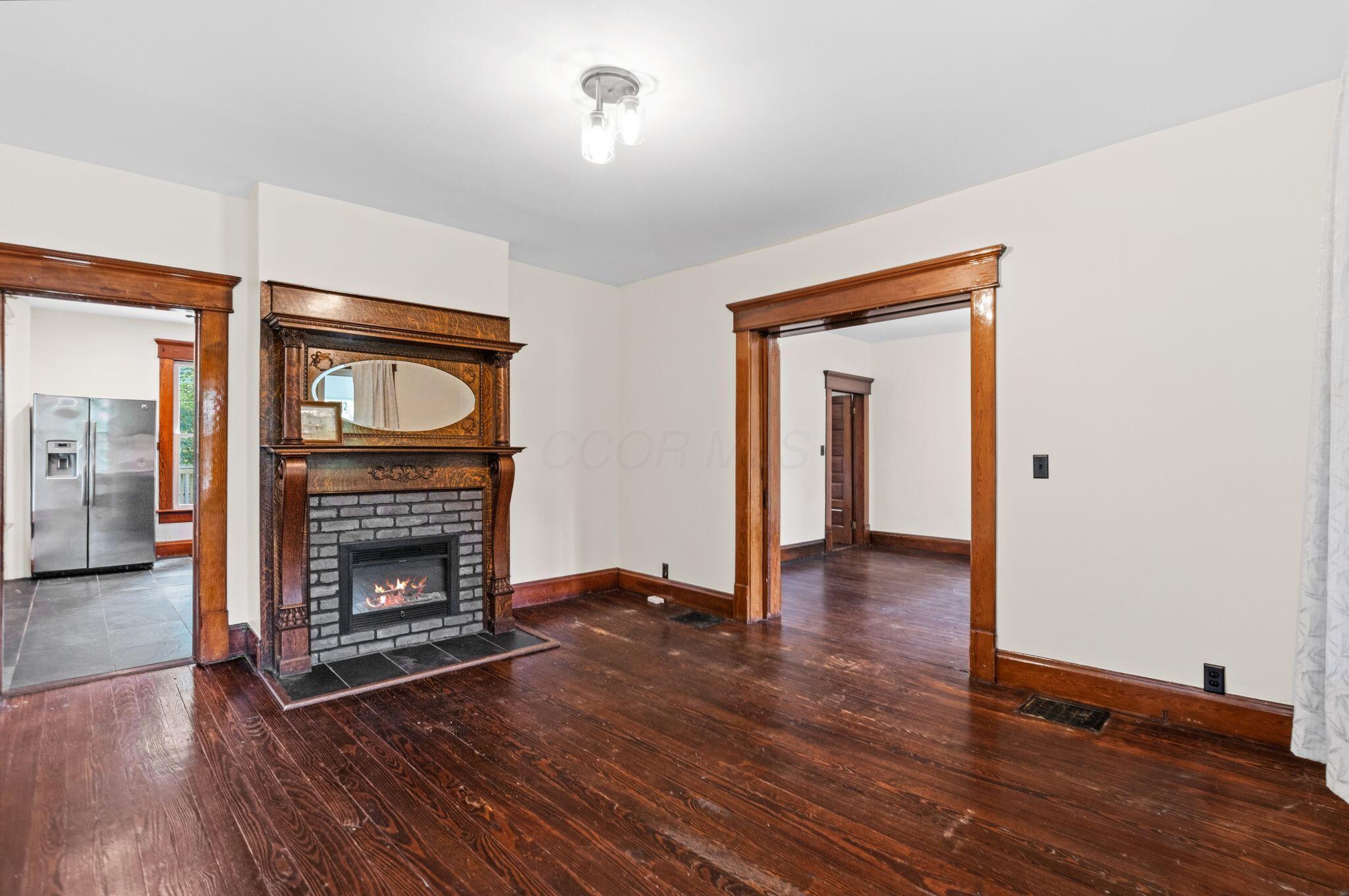 107 Price Road Columbus, OH 43230 - Photo 7 of 51 Hardwood-finish flooring throughout, complemented by a decorative fireplace featuring an ornate wood mantel and brick surround