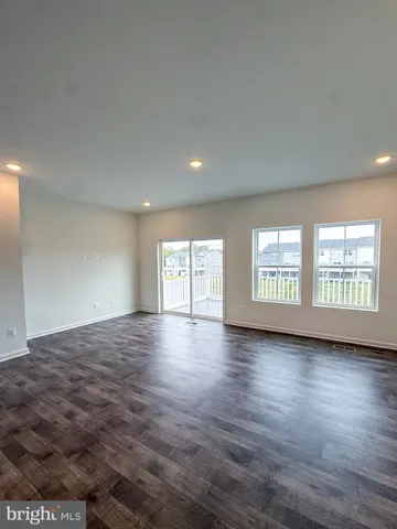 a view of an empty room with wooden floor and window