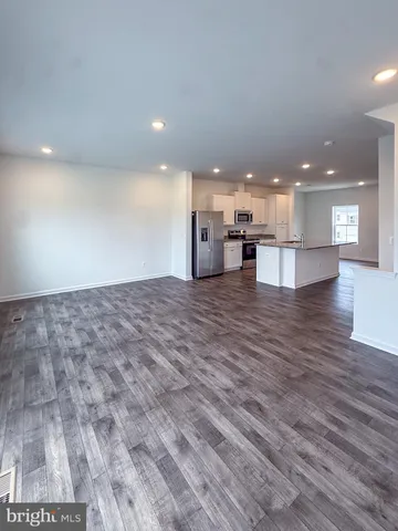 a view of a kitchen with kitchen island a sink wooden floor and living room view