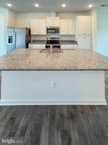 a kitchen with stainless steel appliances a sink a stove a microwave a center island and cabinets