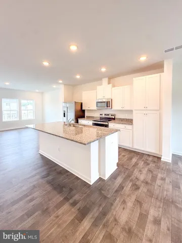 a large white kitchen with kitchen island a sink a stove and a refrigerator