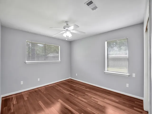 a view of an empty room with a window and wooden floor