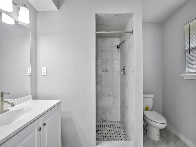 a bathroom with a granite countertop sink toilet and shower
