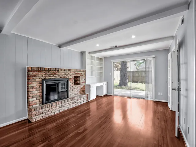 a living room with wooden floor and a fireplace