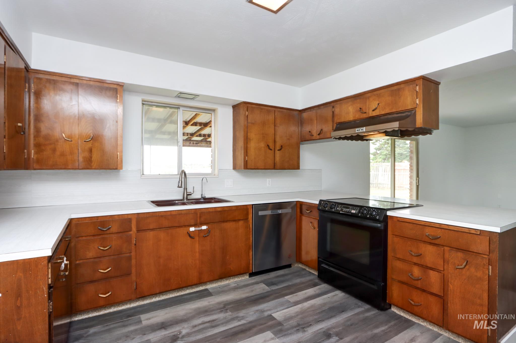 801 Thompson Avenue Nyssa, OR 97913 - Photo 10 of 46 Kitchen featuring L-shaped wood cabinetry, white countertops, stainless steel dishwasher, black electric range, and wood-finish flooring