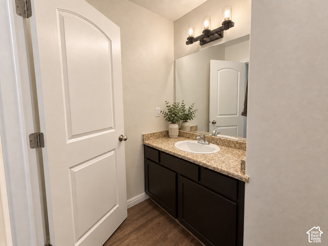 11689 South Shadow View Lane Draper, UT 84020 - Photo 11 of 25 Wood-finish flooring, dark wood vanity with ample storage, integrated sink, speckled countertop, and a three-light fixture