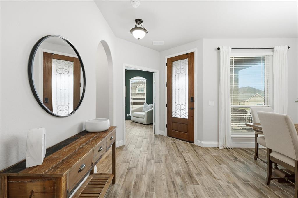 924 Timber Ridge Drive Justin, TX 76247 - Photo 6 of 32 Entryway featuring a wood-finish door with decorative glass inserts, wood-finish flooring, a contemporary ceiling light fixture, and arched doorways