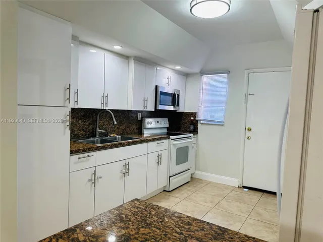 a kitchen with granite countertop white cabinets and stainless steel appliances