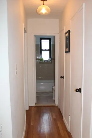 a view of a hallway with wooden floor and closet