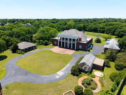 an aerial view of residential houses with outdoor space and trees all around