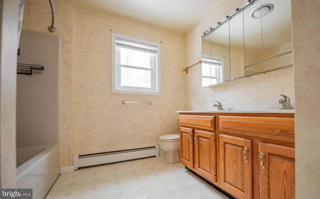 a bathroom with a granite countertop sink a toilet and with mirror