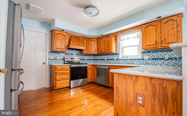 a kitchen with granite countertop wooden cabinets a sink a window and stainless steel appliances