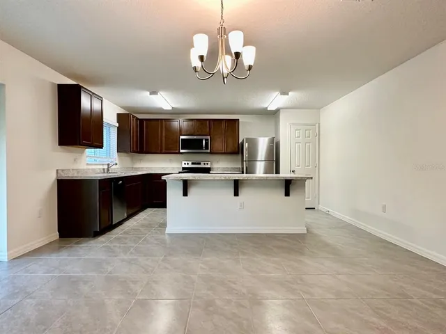 a large kitchen with stainless steel appliances granite countertop a sink a stove top oven a counter space and cabinets