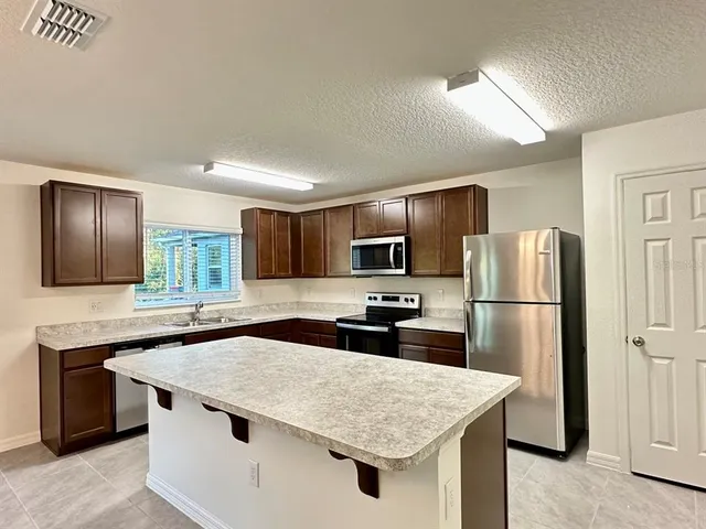 a kitchen with stainless steel appliances granite countertop a sink stove refrigerator and cabinets