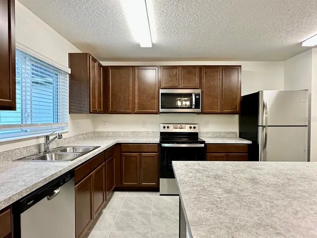 a kitchen with granite countertop a refrigerator and a sink