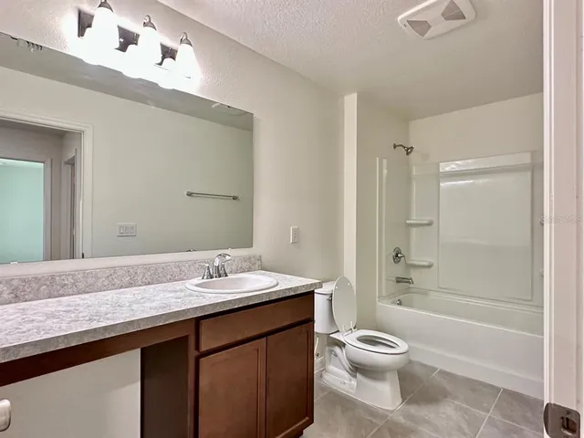 a bathroom with a granite countertop sink toilet a large mirror a bathtub and shower