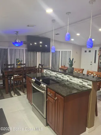 a living room with furniture a chandelier and a dining table with kitchen view