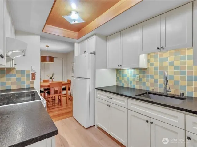 a kitchen with granite countertop a refrigerator a stove a dining table and chairs