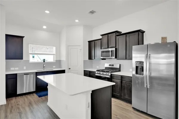a kitchen with stainless steel appliances a sink stove refrigerator and cabinets