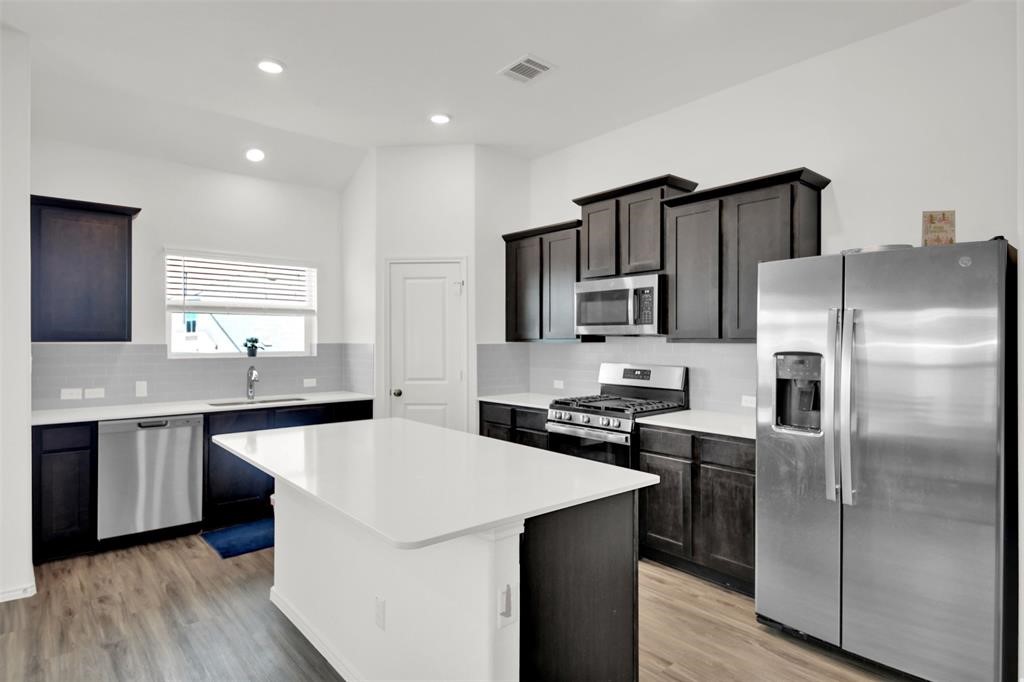 937 Mallow Road Leander, TX 78641 - Photo 16 of 30 a kitchen with stainless steel appliances a sink stove refrigerator and cabinets