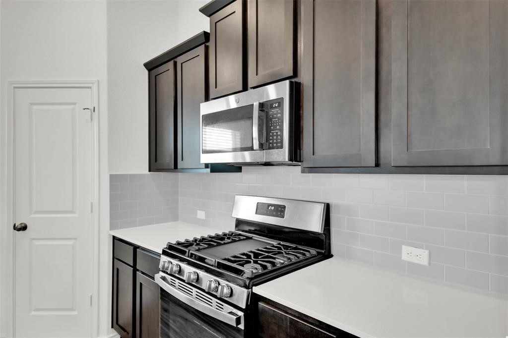 937 Mallow Road Leander, TX 78641 - Photo 18 of 30 a kitchen with granite countertop a stove and a microwave