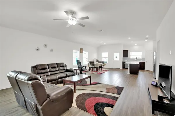 a living room with furniture a flat screen tv and kitchen view
