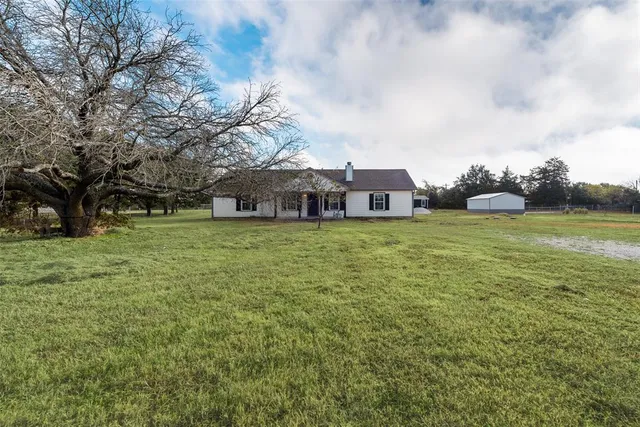 a view of a house with a big yard and large trees