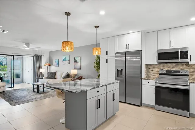 a kitchen with stainless steel appliances granite countertop a stove a sink a refrigerator and a fireplace