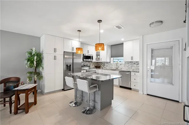 a kitchen with stainless steel appliances kitchen island granite countertop a sink and a refrigerator