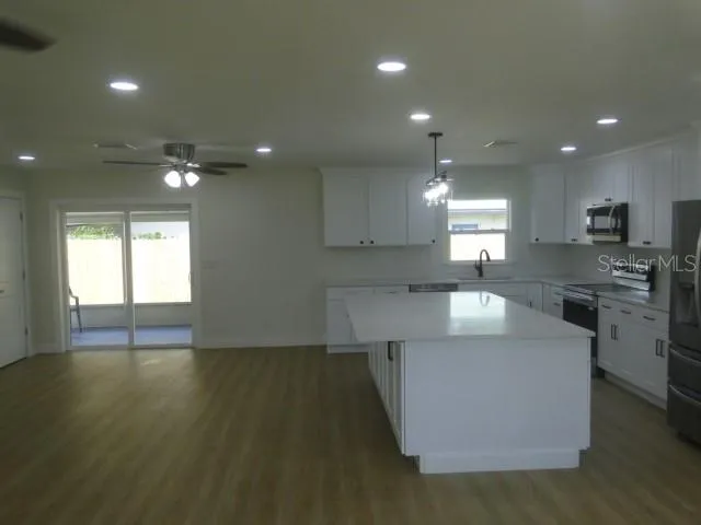 a large kitchen with stainless steel appliances a large counter top a stove a chimney a sink and a refrigerator