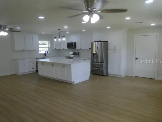 a view of a kitchen with stainless steel appliances granite countertop a large counter top a stove and a sink
