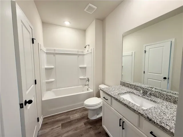 a bathroom with a granite countertop sink a toilet and shower